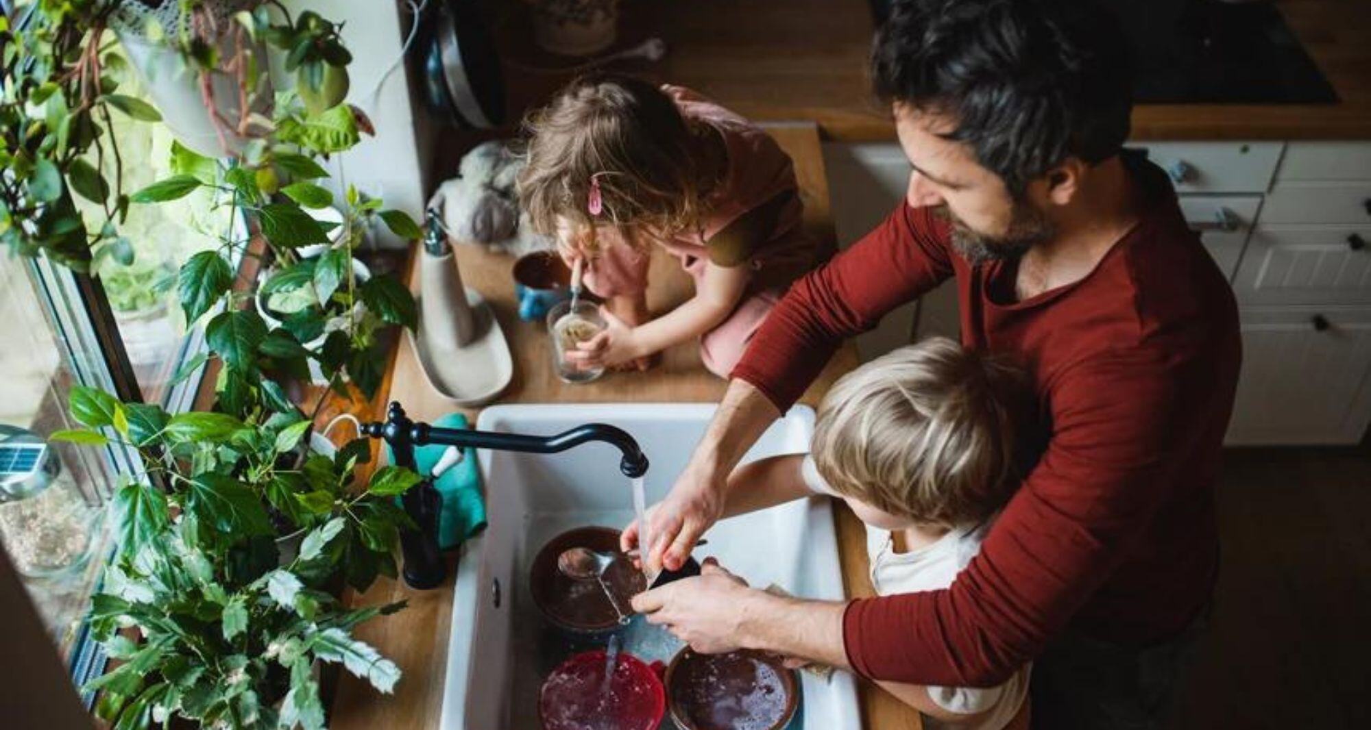 Vue de dessus de père avec deux petits enfants lavant la vaisselle à la maison - offre d'électricité verte