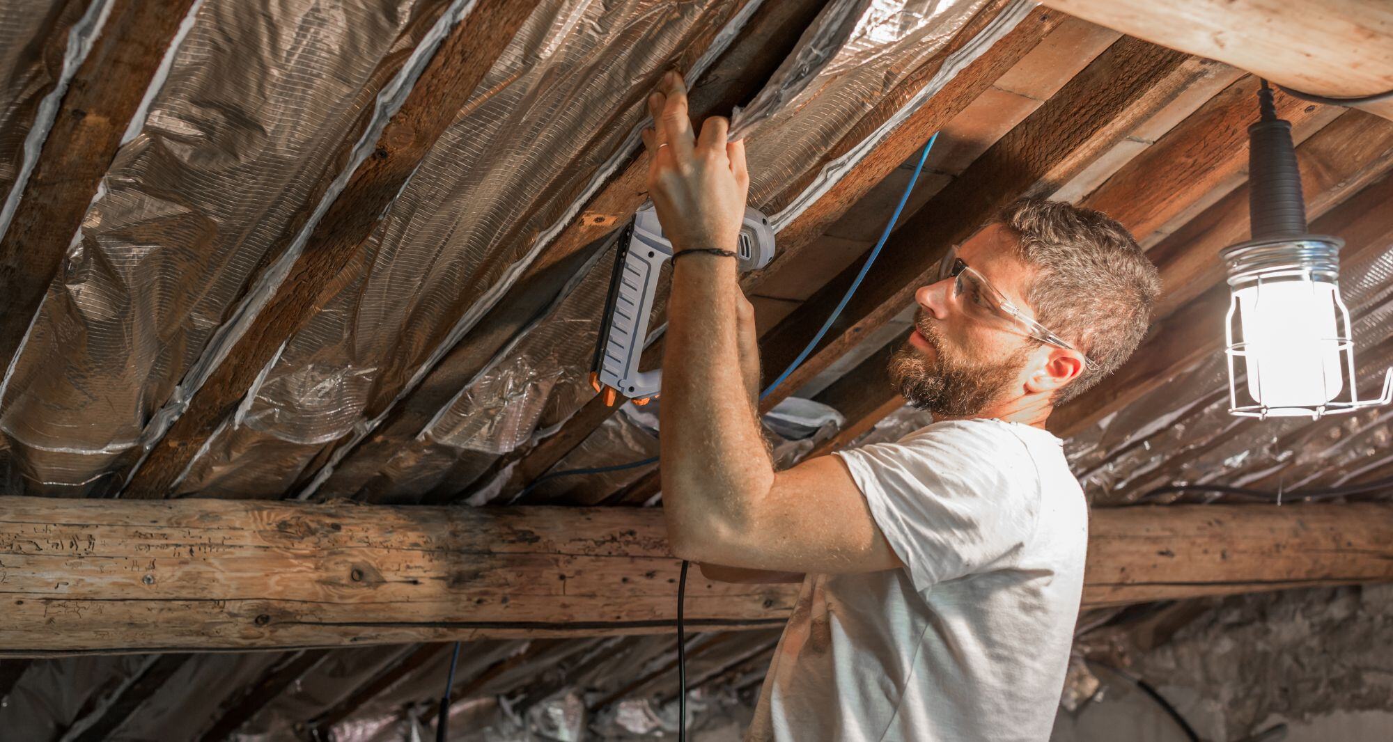 un homme qui effectue des travaux de rénovation d'une toiture de maison - travaux economie energie